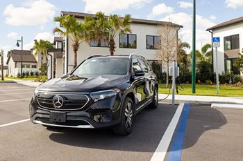 A black Mercedes-Benz EQC is parked in a parking spot with a charging station  at The Hadley - North Port, FL Apartments, North Port 34287